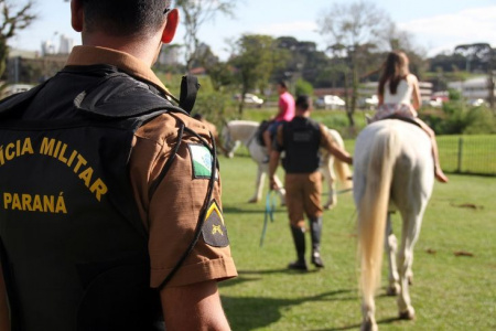 Policial Realizando treinamento de equitação com crianças.